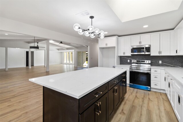 kitchen featuring a center island, backsplash, hanging light fixtures, light hardwood / wood-style flooring, and appliances with stainless steel finishes