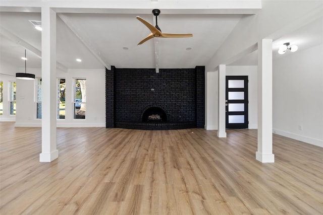 unfurnished living room featuring vaulted ceiling with beams, ceiling fan, light hardwood / wood-style flooring, and a brick fireplace