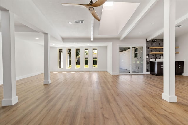 unfurnished living room with ceiling fan, beam ceiling, and light wood-type flooring