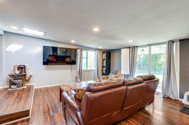 living room featuring hardwood / wood-style flooring, a skylight, and a textured ceiling