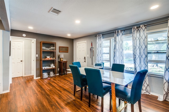 dining room with dark wood-type flooring and a textured ceiling