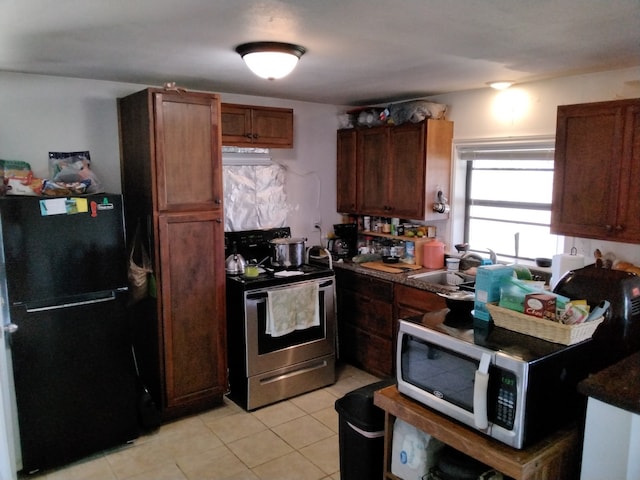 kitchen with electric range, black refrigerator, light tile patterned flooring, and sink