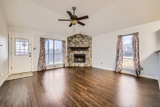 unfurnished living room featuring lofted ceiling, a stone fireplace, dark hardwood / wood-style flooring, and ceiling fan