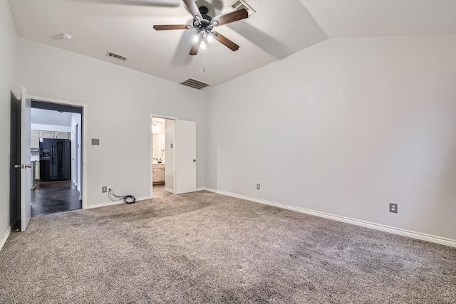 unfurnished bedroom with lofted ceiling, ensuite bathroom, black refrigerator with ice dispenser, carpet flooring, and ceiling fan