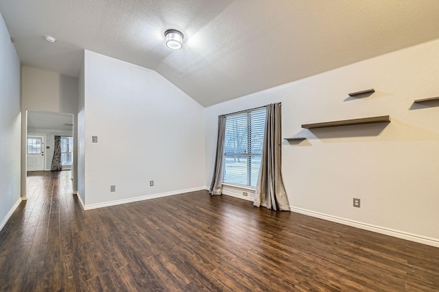 interior space with lofted ceiling, dark hardwood / wood-style flooring, and a textured ceiling