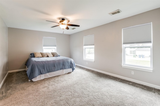 carpeted bedroom with multiple windows and ceiling fan