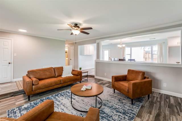 living room with ceiling fan with notable chandelier, dark hardwood / wood-style flooring, and ornamental molding