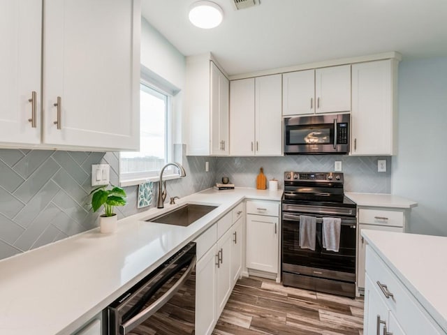 kitchen featuring sink, appliances with stainless steel finishes, tasteful backsplash, white cabinetry, and wood-type flooring