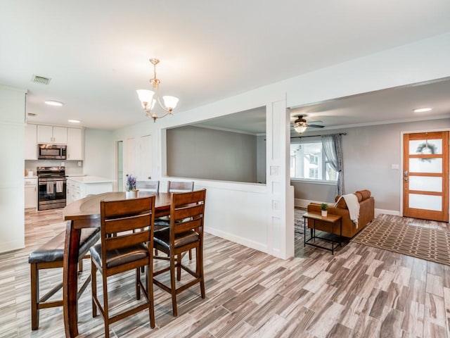 dining space with light hardwood / wood-style floors and ceiling fan with notable chandelier