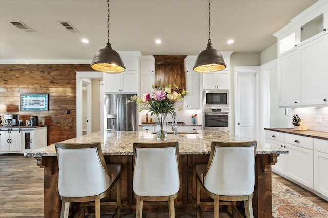 kitchen featuring a kitchen island with sink, decorative light fixtures, and stainless steel appliances