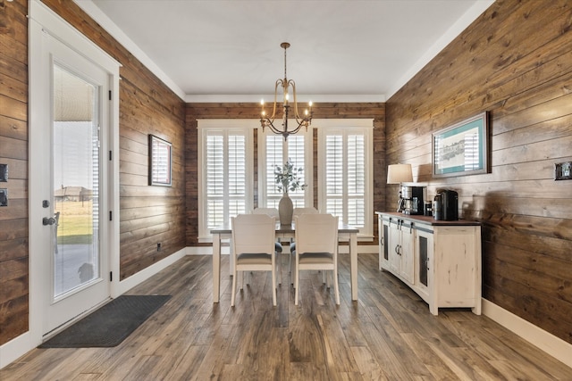 dining area with dark hardwood / wood-style flooring, wooden walls, and a chandelier