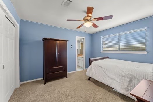 bedroom with ceiling fan, connected bathroom, light carpet, and a closet