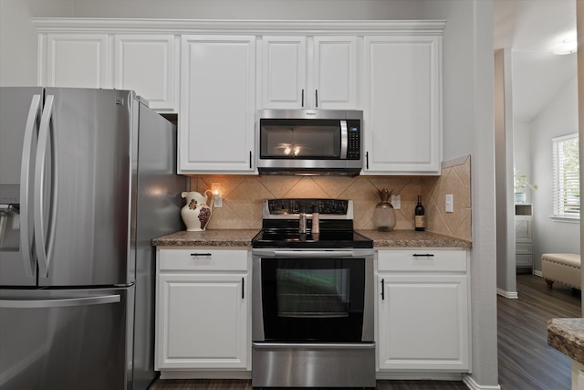 kitchen with white cabinets, stainless steel appliances, and dark stone countertops