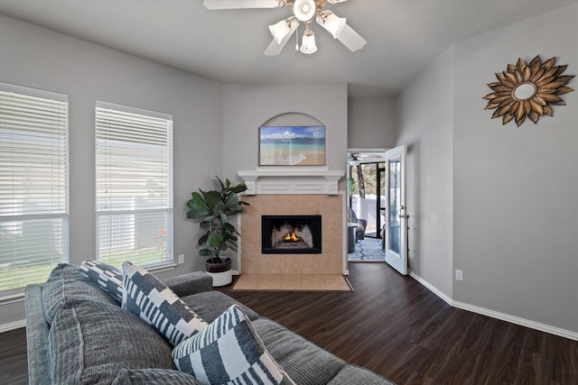 living room with ceiling fan, dark wood-type flooring, a wealth of natural light, and a tiled fireplace