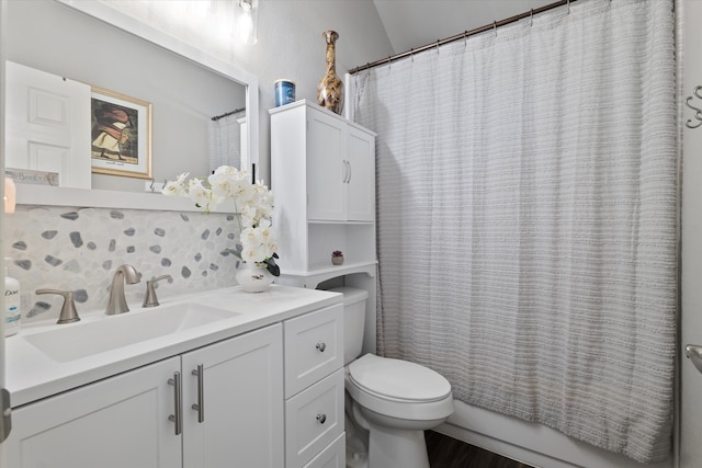 bathroom with decorative backsplash, vanity, vaulted ceiling, and toilet