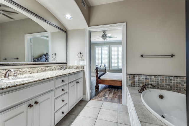 bathroom featuring tile patterned flooring, vanity, ceiling fan, and tiled tub