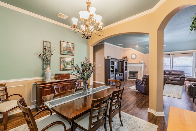 dining area featuring dark hardwood / wood-style floors, a notable chandelier, crown molding, lofted ceiling, and a tiled fireplace