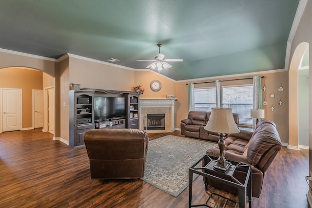 living room featuring a tile fireplace, crown molding, vaulted ceiling, dark hardwood / wood-style floors, and ceiling fan