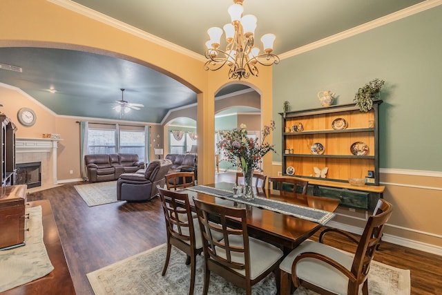 dining room featuring a tile fireplace, lofted ceiling, ceiling fan with notable chandelier, and dark wood-type flooring