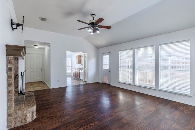 unfurnished living room with lofted ceiling, sink, a brick fireplace, dark hardwood / wood-style floors, and ceiling fan