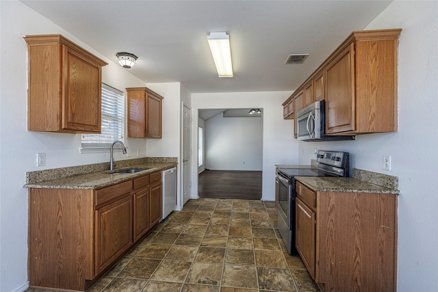 kitchen featuring appliances with stainless steel finishes, dark stone counters, and sink