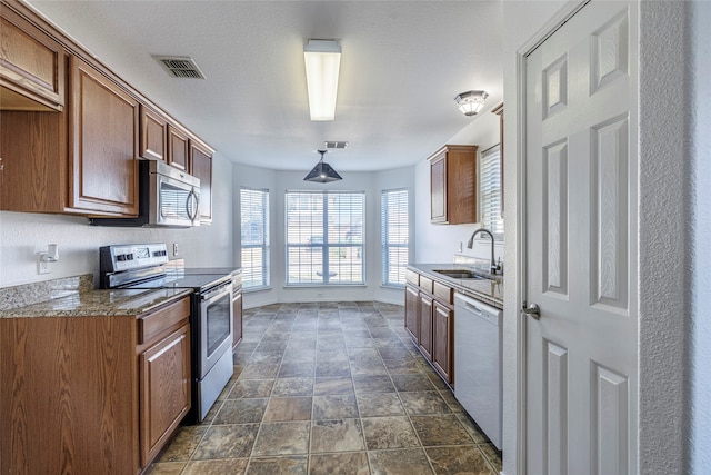 kitchen featuring decorative light fixtures, stainless steel appliances, dark stone counters, and sink