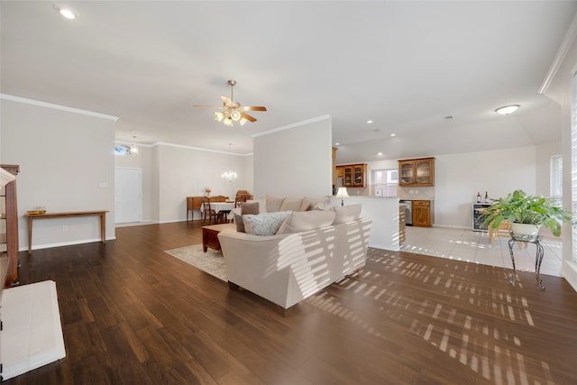 living room with hardwood / wood-style flooring, ceiling fan with notable chandelier, and ornamental molding