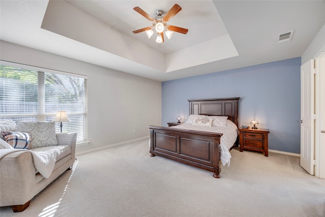 carpeted bedroom featuring a tray ceiling and ceiling fan