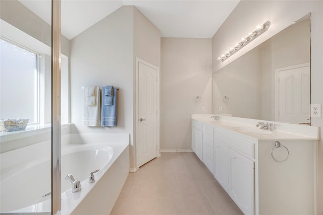 bathroom with tile patterned floors, a tub, and vanity