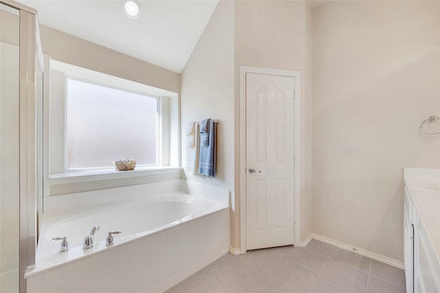 bathroom featuring tile patterned flooring, a bathtub, lofted ceiling, and vanity