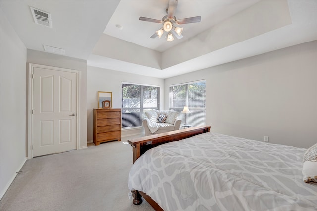 carpeted bedroom featuring ceiling fan and a tray ceiling