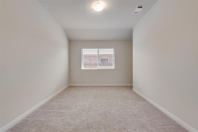 carpeted spare room with lofted ceiling