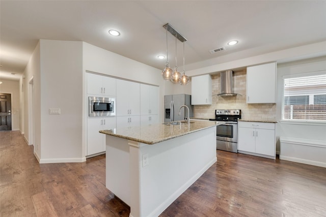 kitchen featuring white cabinets, hanging light fixtures, wall chimney range hood, and appliances with stainless steel finishes