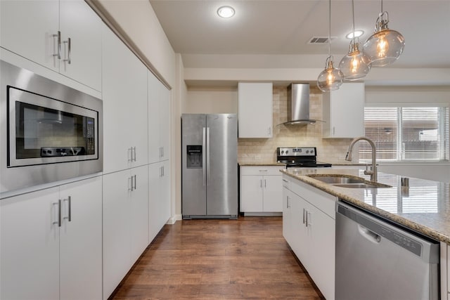 kitchen with white cabinets, sink, wall chimney exhaust hood, a wealth of natural light, and appliances with stainless steel finishes