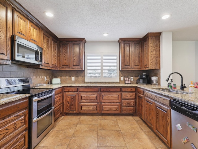 305 Dena, Krugerville, TX 76227 - kitchen with appliances with stainless steel finishes, a sink, backsplash, a textured ceiling, and light stone counters