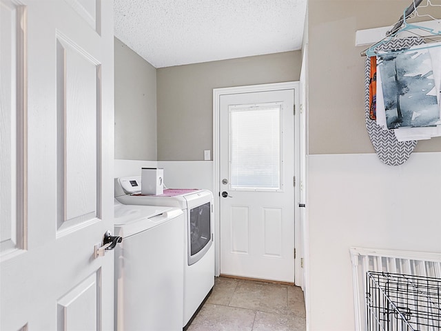 clothes washing area featuring independent washer and dryer, a textured ceiling, and light tile patterned floors