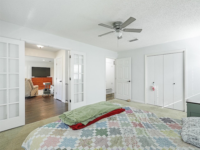 bedroom with a textured ceiling, ceiling fan, and dark wood-type flooring