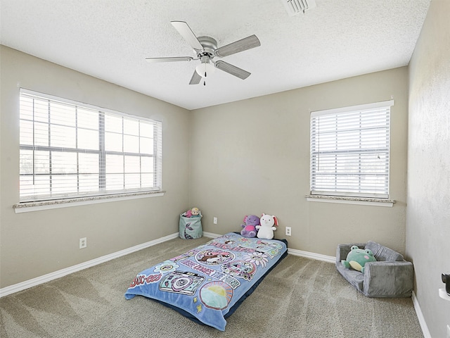 bedroom featuring multiple windows, ceiling fan, carpet floors, and a textured ceiling