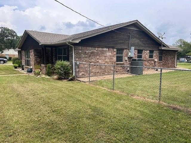 view of side of property featuring central AC and a yard