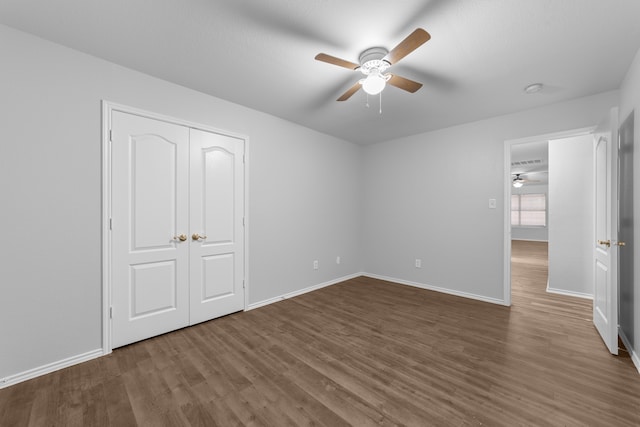 unfurnished bedroom with dark hardwood / wood-style flooring, a closet, and ceiling fan