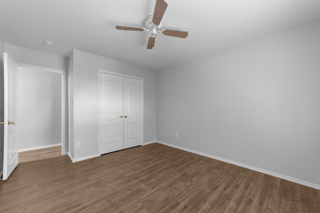 unfurnished bedroom featuring ceiling fan, dark hardwood / wood-style flooring, and a closet