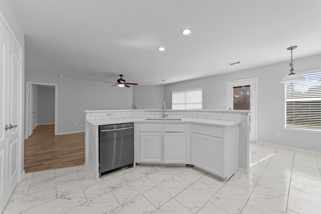 kitchen with sink, light hardwood / wood-style flooring, stainless steel dishwasher, pendant lighting, and white cabinets