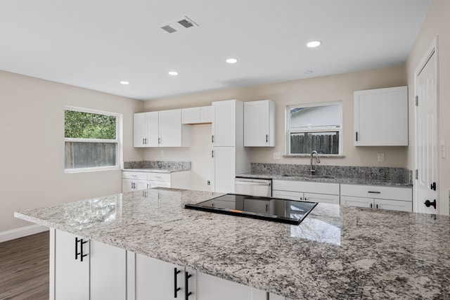 kitchen featuring light stone countertops, dark wood-type flooring, sink, dishwasher, and white cabinets