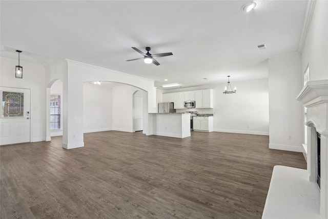 unfurnished living room with ceiling fan with notable chandelier, dark hardwood / wood-style flooring, and ornamental molding