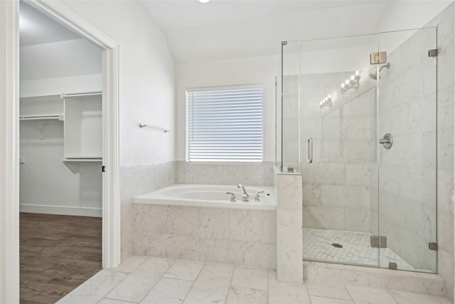 bathroom featuring wood-type flooring, independent shower and bath, and vaulted ceiling