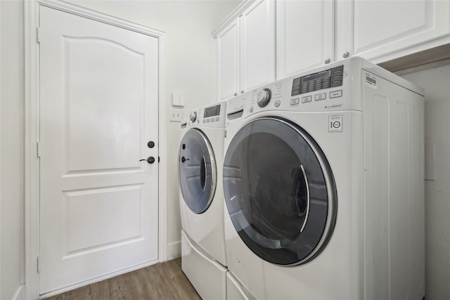 clothes washing area with cabinets, dark wood-type flooring, and washing machine and clothes dryer