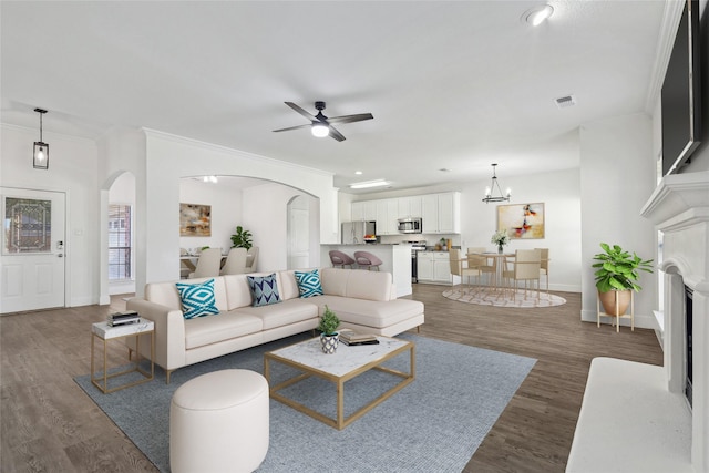 living room with ornamental molding, arched walkways, visible vents, and wood finished floors