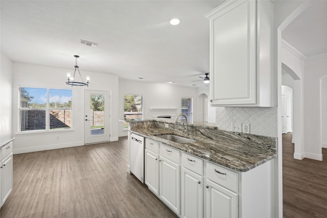 kitchen featuring sink, dark wood-type flooring, stainless steel dishwasher, dark stone counters, and white cabinets