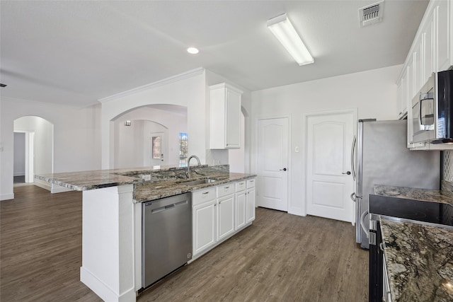 kitchen with dark wood-type flooring, dark stone counters, sink, white cabinetry, and stainless steel appliances