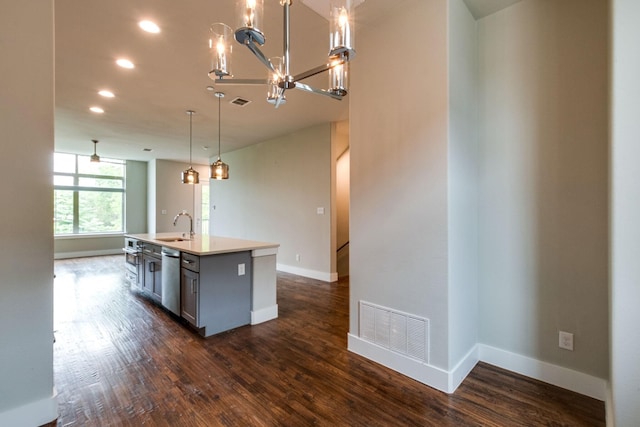 kitchen with stainless steel dishwasher, dark wood-type flooring, sink, decorative light fixtures, and a center island with sink